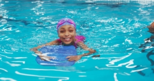 Young child using board to exercise in backyard swimming pool 